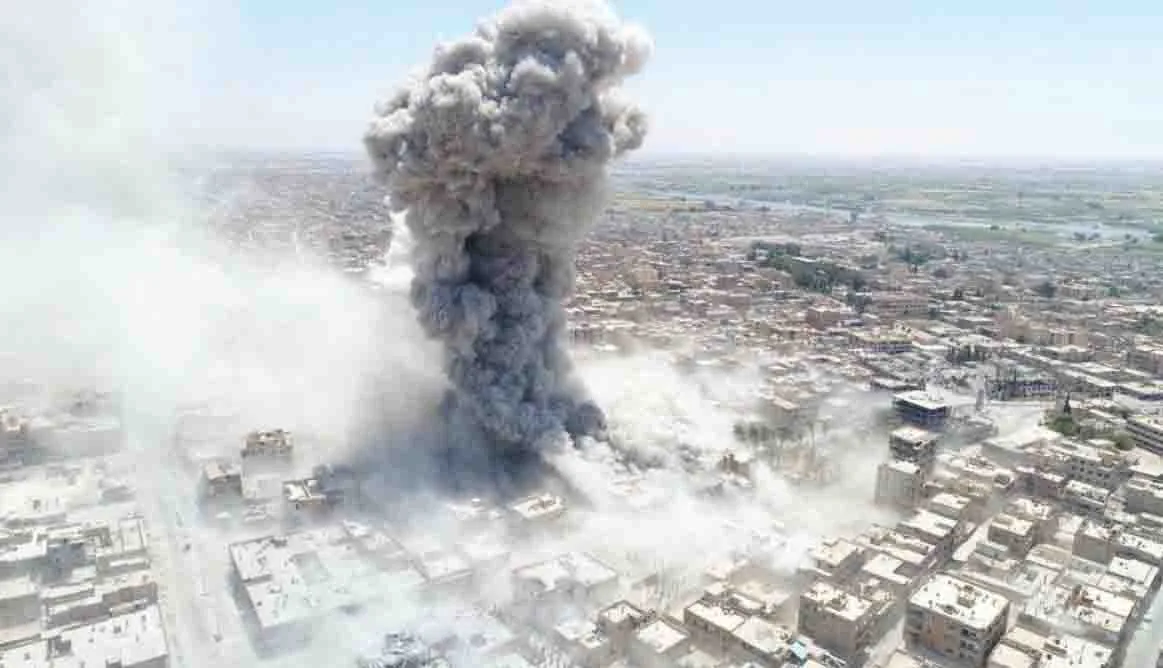 Aerial photograph of Raqqa with a large plume of smoke rising over the damaged city